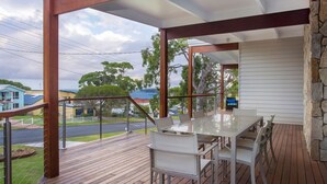 A covered outdoor area with a table and chairs, a stone wall, and a view of houses and trees.