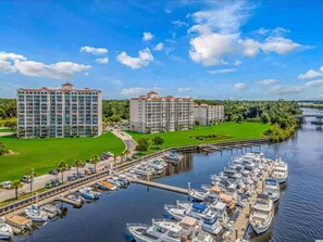 Ein Yachthafen mit mehreren angedockten Booten, umgeben von einem weitläufigen Hotelkomplex mit mehreren Gebäuden und einer grünen Landschaft.