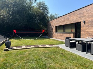 A modern outdoor area with a wooden wall, a red netted structure, and a stone pathway.
