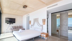 Un dormitorio moderno con una cama grande, televisión, trípode y vistas al balcón.