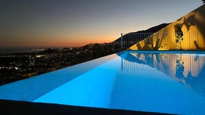 Una piscina con vista despejada a un paisaje urbano y una montaña al fondo.