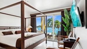 A four-poster bed with a view of the ocean, a dining area with a table and chairs, and a TV mounted on the wall. - Villa 3: islandpropertiesonline: 5-bedroom villa infinity pool & terrace (Maho)