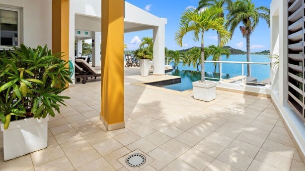A modern outdoor area with a pool, palm trees, and a clear view of the sea. - Villa 3: islandpropertiesonline: 5-bedroom villa infinity pool & terrace (Maho)