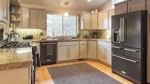 A modern kitchen with granite countertops, stainless steel appliances, and a large window providing natural light. - Private Boat Ramp Access Hot Tub, Fire Pit, Deck River Meadows by Avantstay (Bend)