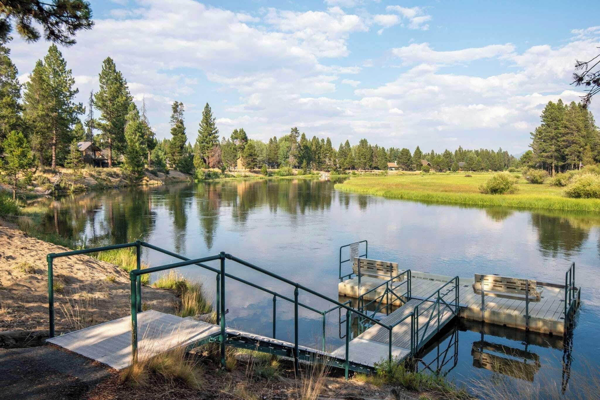 A lakeside property with a dock, a wooden deck, and a grassy area.