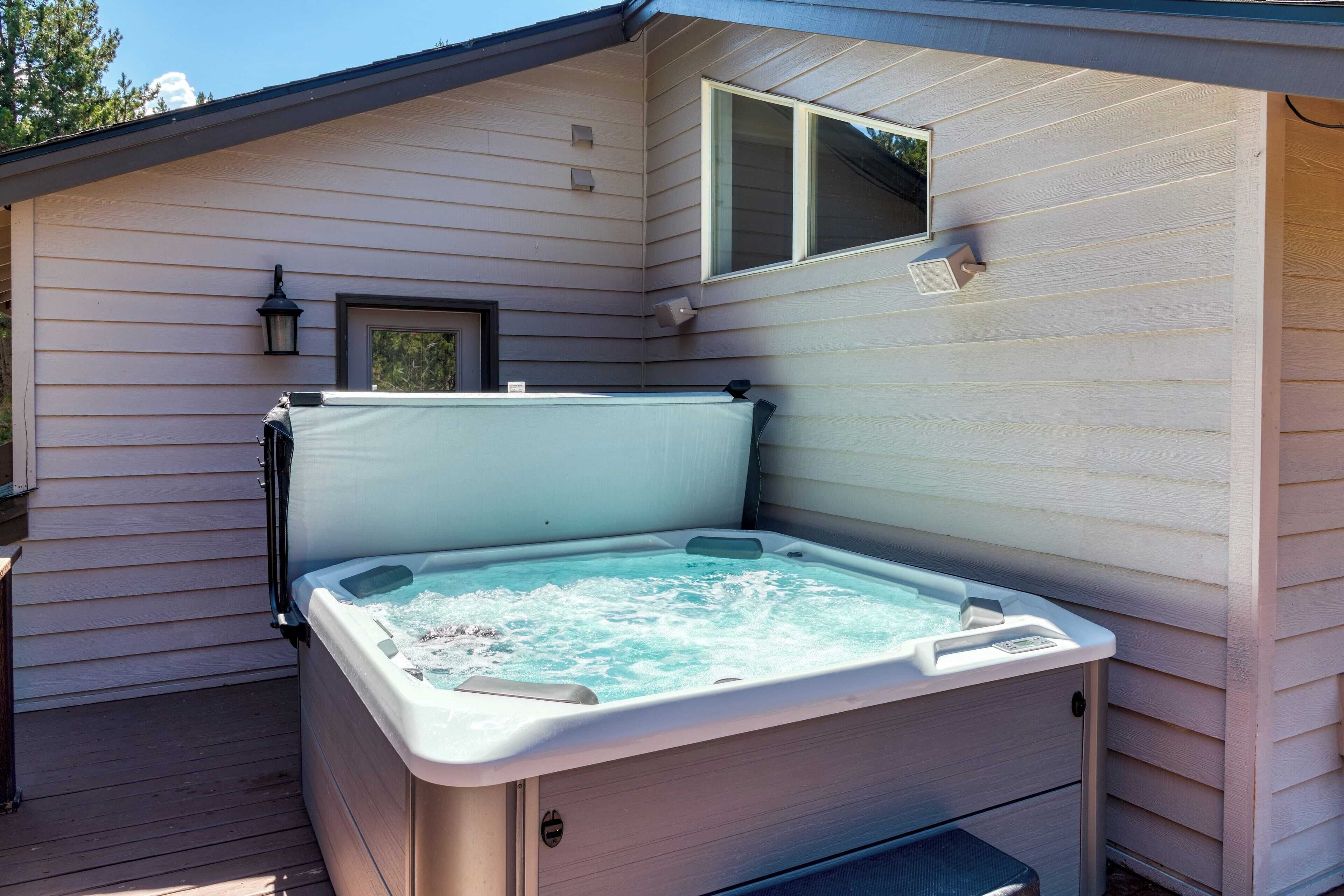 Ein Whirlpool in einem überdachten Außenbereich mit Holzterrasse, kleinem Fenster und einer Wandleuchte.