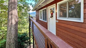 A wooden cabin with a deck, a white door, and a 'NO PETS' sign. - Beautiful Cabin in Chalet Village. Hot Tub, 3 Decks, Stunning Mountain Views  (Gatlinburg)