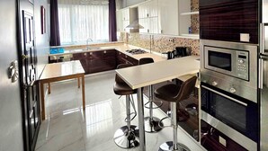 Cozinha moderna com piso de mármore, eletrodomésticos de aço inoxidável e um espaço de refeições com banquetas.