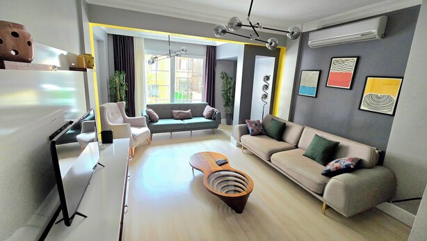 Uma sala de estar moderna com sofá, poltronas, mesa de centro e área de jantar com mesa e cadeiras.