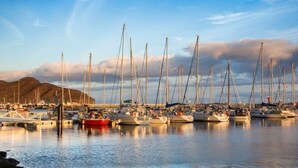 A marina with multiple sailboats docked, calm water, and a mountainous backdrop. - Mar&mar apartment with solarium and swimming pool. (Gran Tarajal)