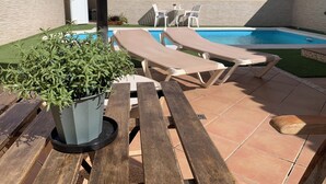 A poolside area with lounge chairs, a potted plant, and a tiled patio. - Mar&mar apartment with solarium and swimming pool. (Gran Tarajal)