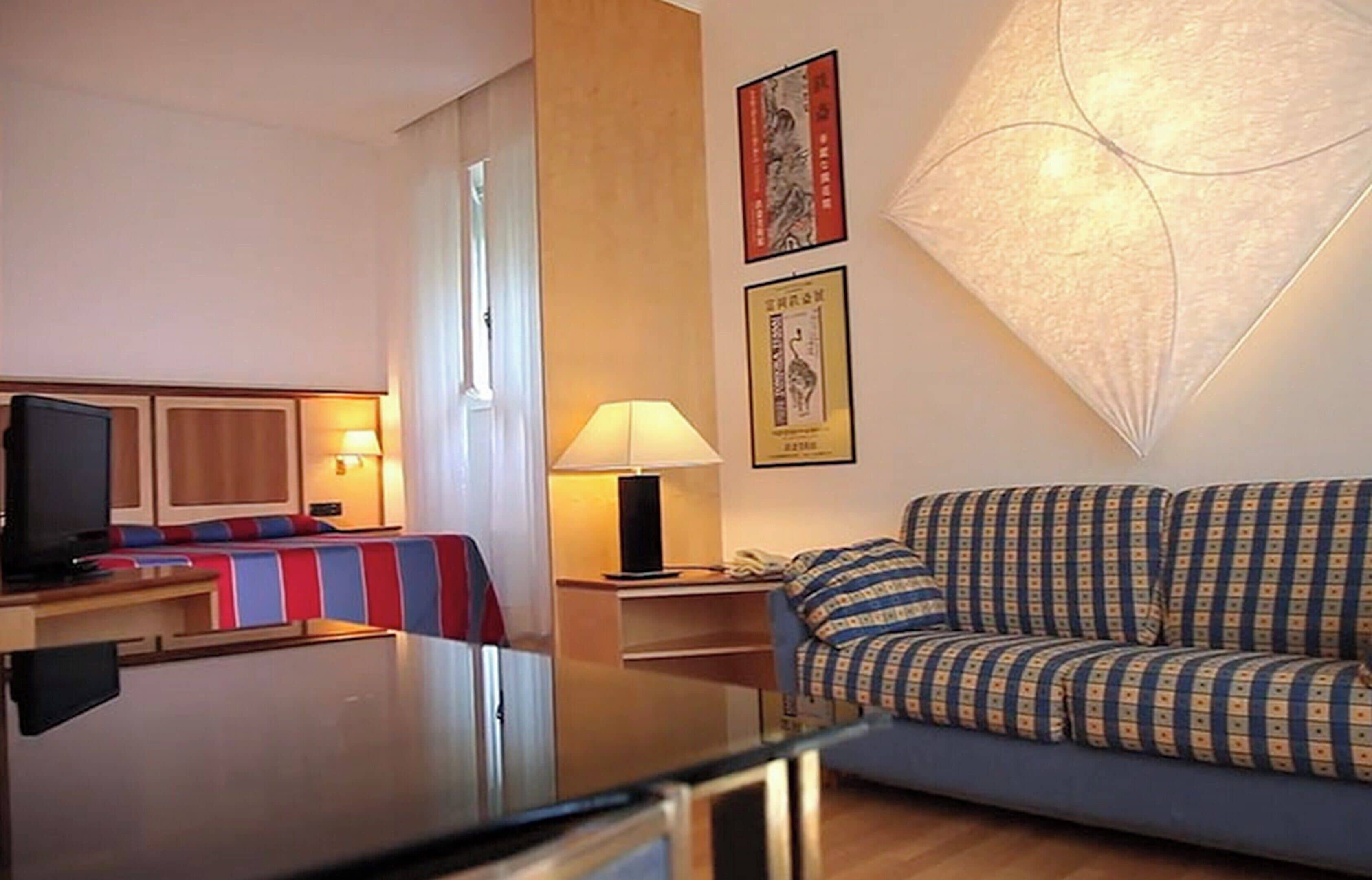 Een hotelkamer met een bank, een televisie, een bureau en een lamp.