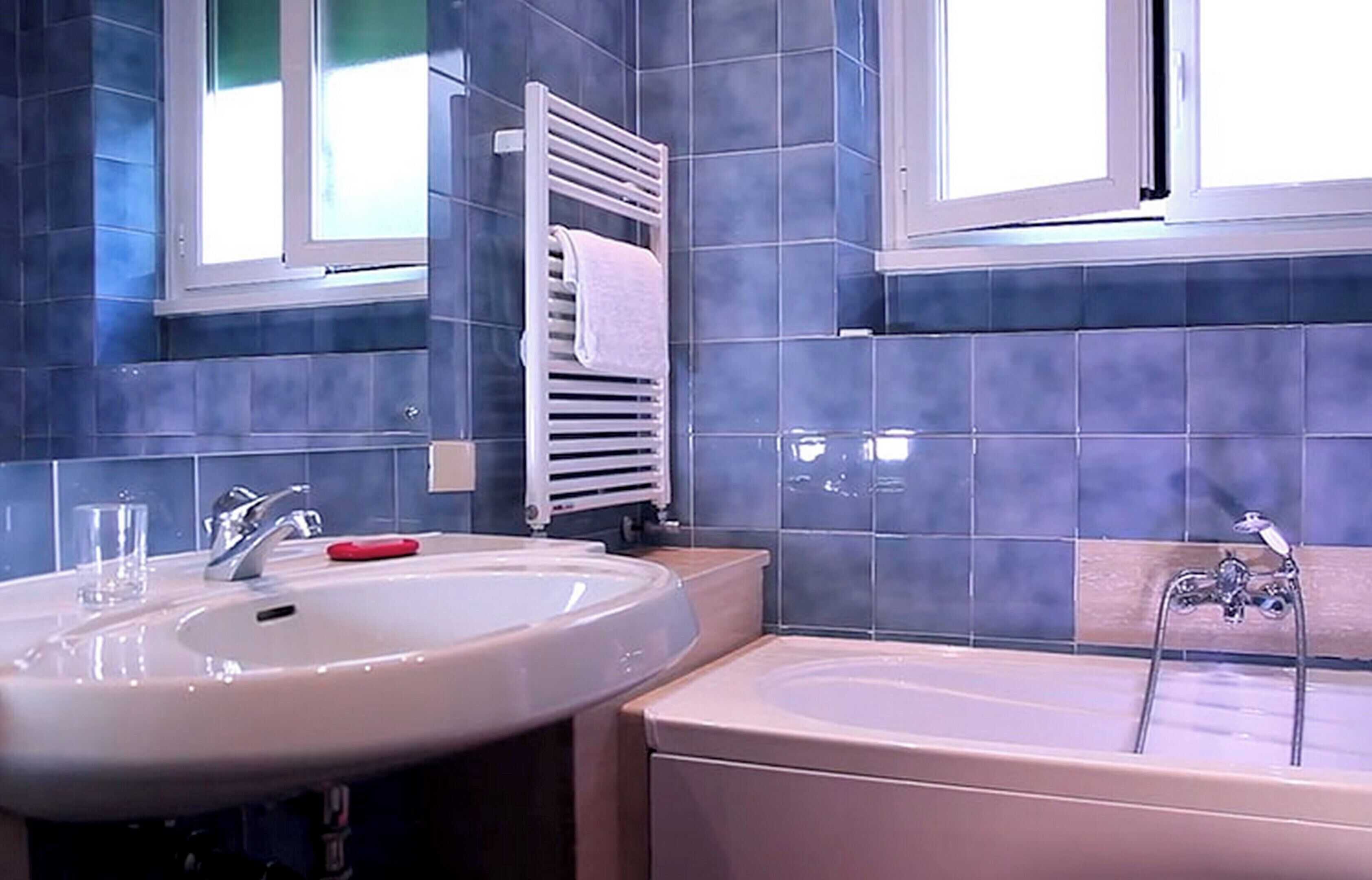 A bathroom with a large sink, a bathtub, and a towel rack.