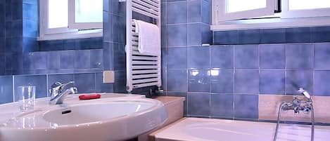 A bathroom with a large sink, a bathtub, and a towel rack.