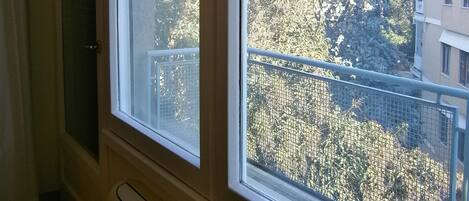 Une fenêtre donnant sur des arbres et des immeubles.
