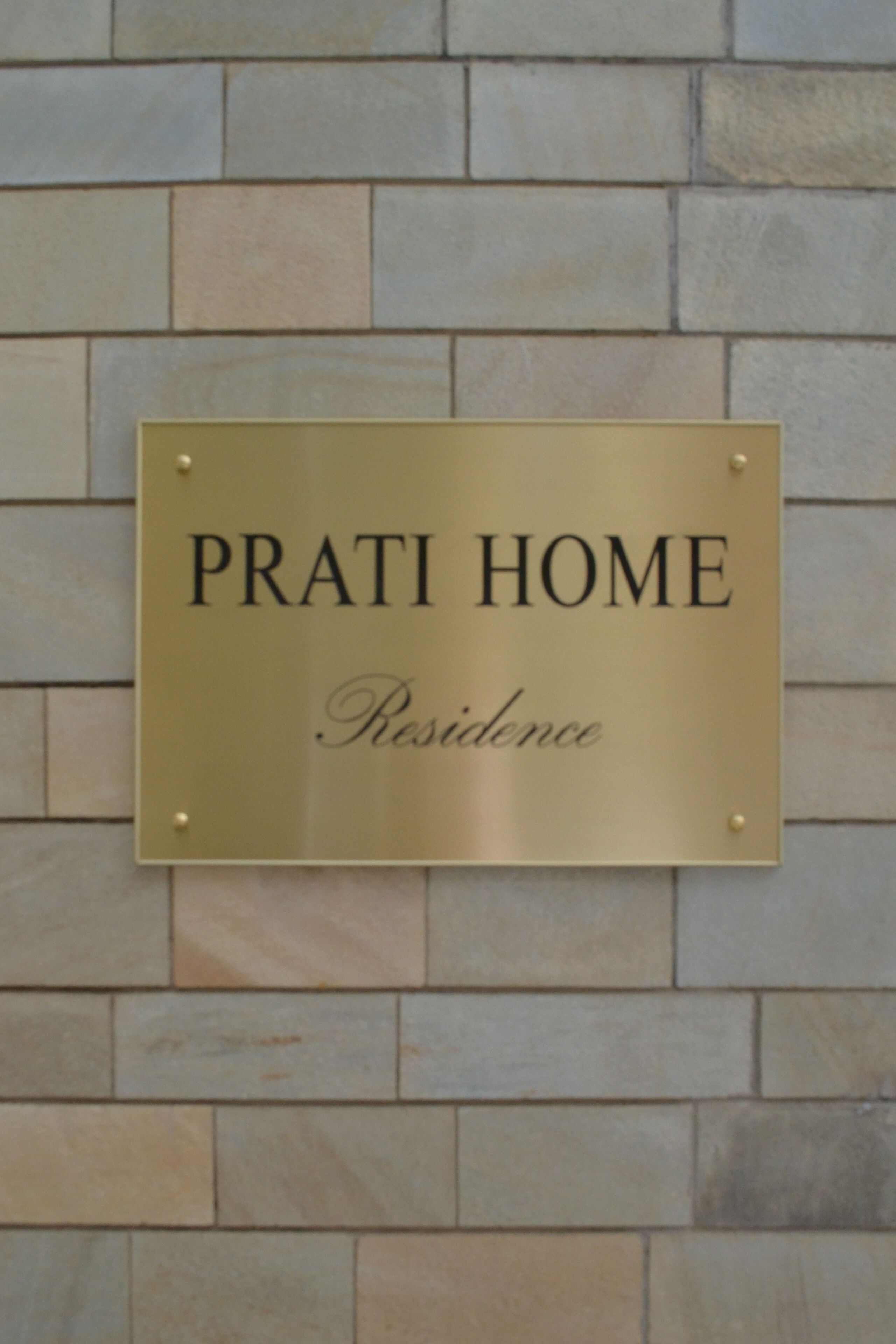 A plaque on a stone wall that reads "PRATI HOME Residence".