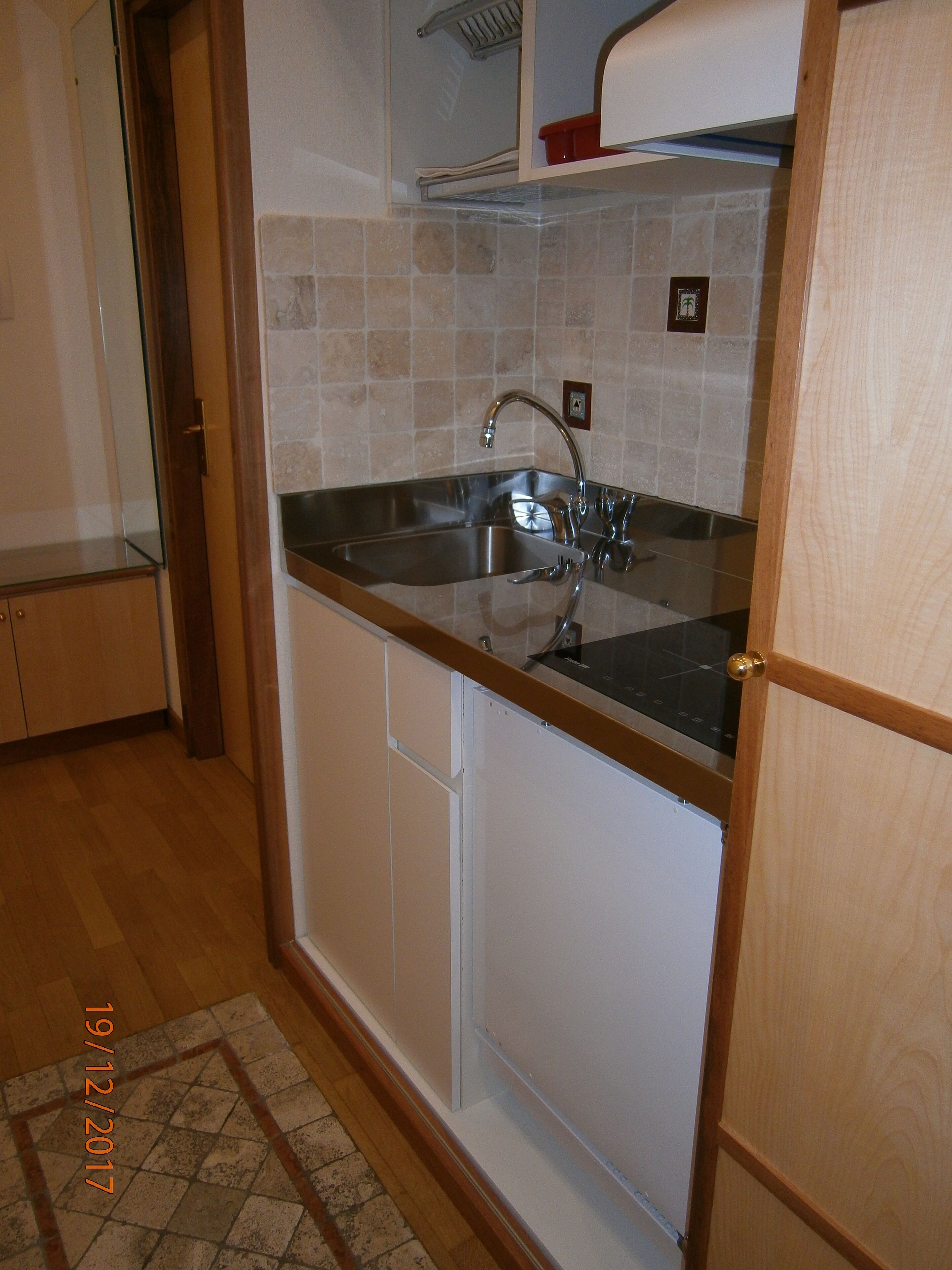 A compact kitchen with a built-in sink, wooden cabinets, and a tiled backsplash.