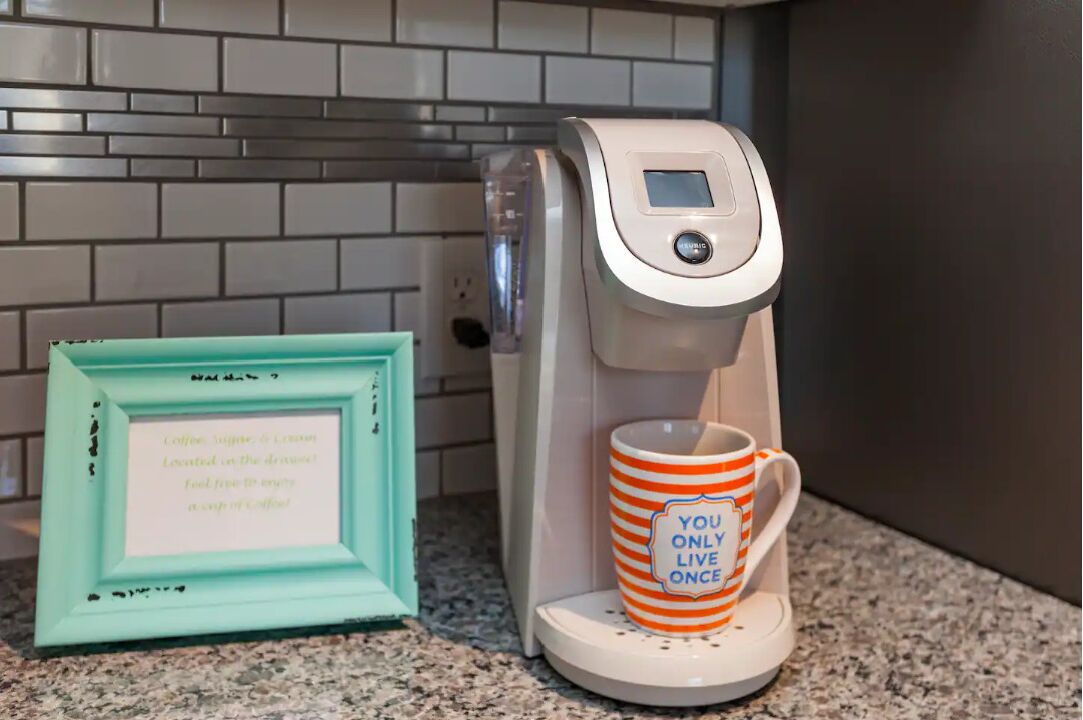 Een koffiezetapparaat met een digitaal scherm, een lijst met een fotokader en een mok met een motiverende quote.