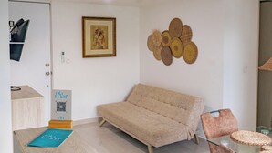 Ein modernes Wohnzimmer mit einer Couch, einem Esstisch mit Glasplatte und einem Wanddekor.
