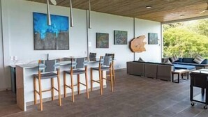 Eine moderne Küche mit Barhocker, einem Essbereich mit einer Couch und Kunstwerken an den Wänden.