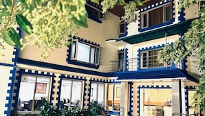 Un edificio de varios pisos con patio interior, que presenta una paleta de colores azul y beige, ventanas amplias y zonas de estar al aire libre.