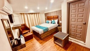 Una habitación de hotel con una cama de madera, una mesita de noche, una silla, un escritorio pequeño y un armario.