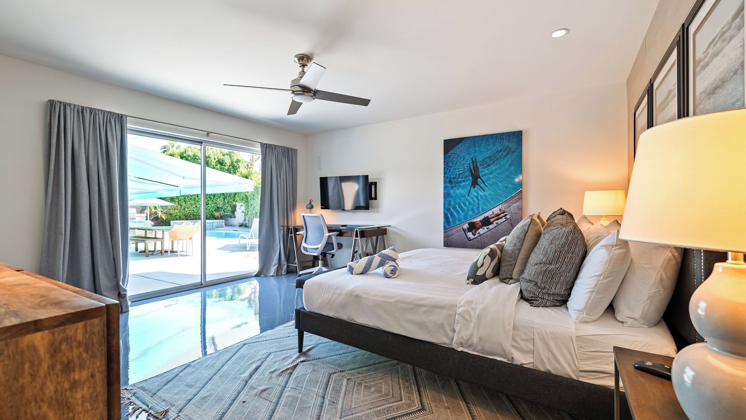 Une chambre d’hôtel équipée d’un lit, d’un bureau, d’une chaise, d’une télévision et offrant une vue sur une piscine extérieure.