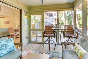 Eine überdachte Veranda mit Korbmöbeln, einem Esstisch und Blick auf den Garten.