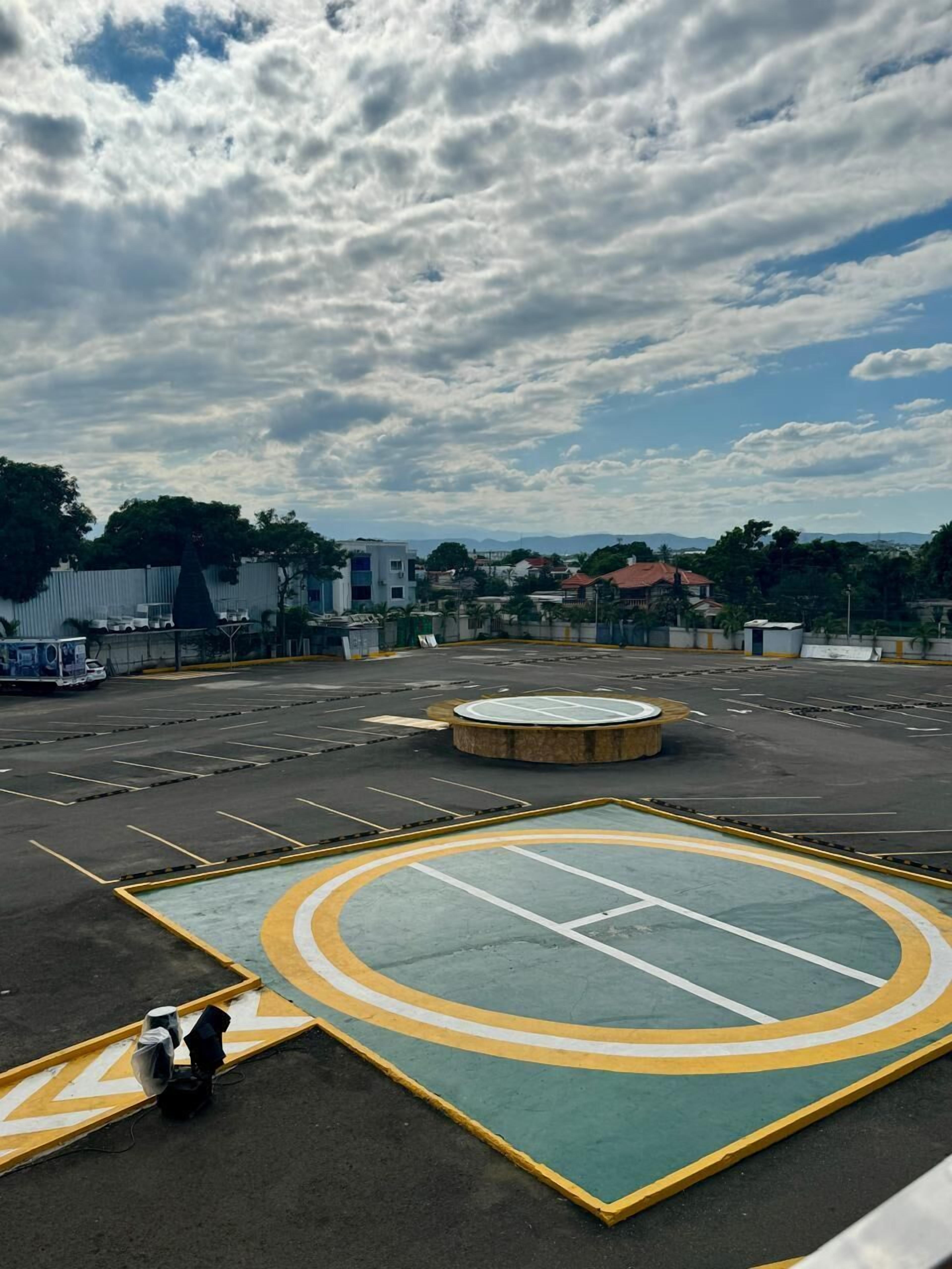 A parking lot with a basketball court, surrounded by buildings and trees.