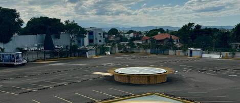 Un estacionamiento con cancha de baloncesto, rodeado de edificios y árboles.