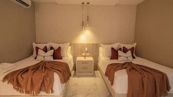 Ein Hotelzimmer mit zwei Betten, einem Nachttisch, einer Lampe und einer Wandklimaanlage.