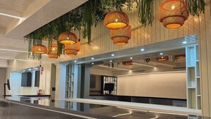 Una moderna zona de recepción con una larga barra, lámparas de mimbre colgantes e iluminación empotrada en el techo.