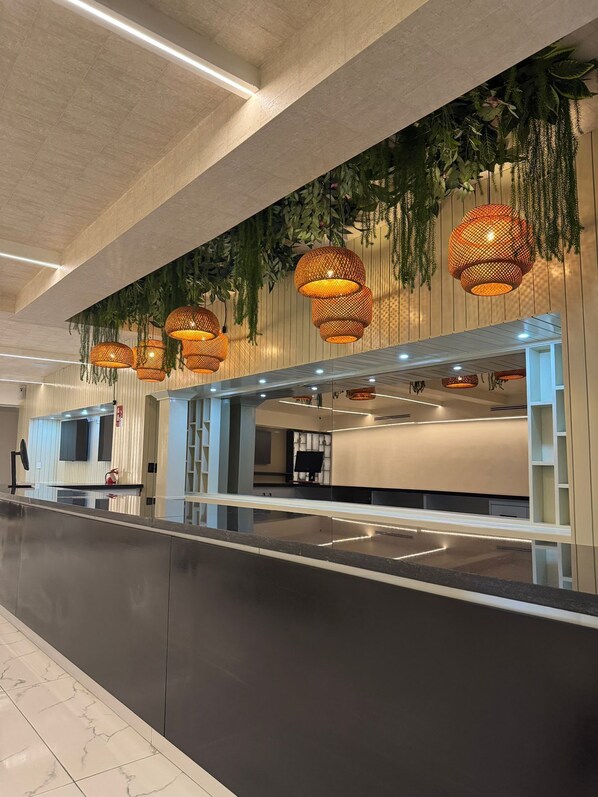 A modern reception area with a long counter, hanging wicker lamps, and a ceiling with recessed lighting.