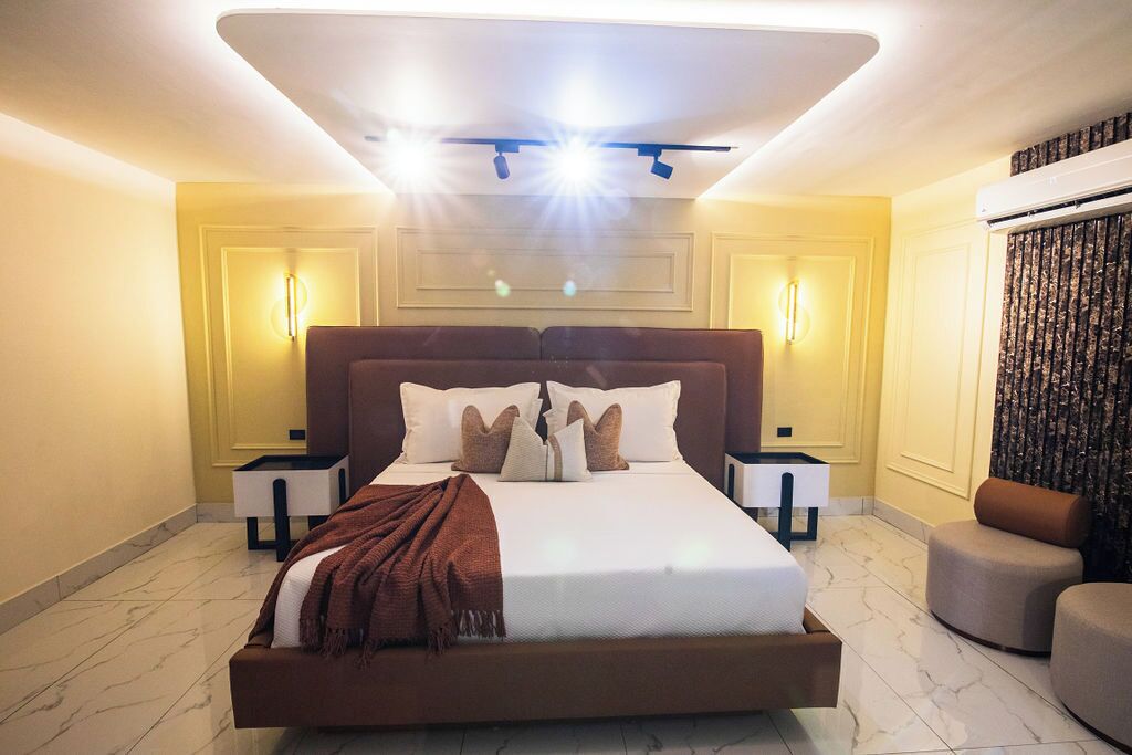 A modern bedroom with a large bed, bedside tables, and a ceiling light fixture.