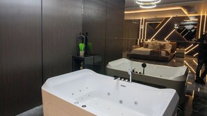Un baño moderno con una bañera independiente grande, una bañera más pequeña separada y una zona de ducha con cerramiento de vidrio.