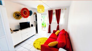 A modern living room with a flat-screen TV, a red sofa, yellow and red curtains, and decorative wall art.