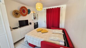 Een slaapkamer met een bed, een televisie en een wandplank.