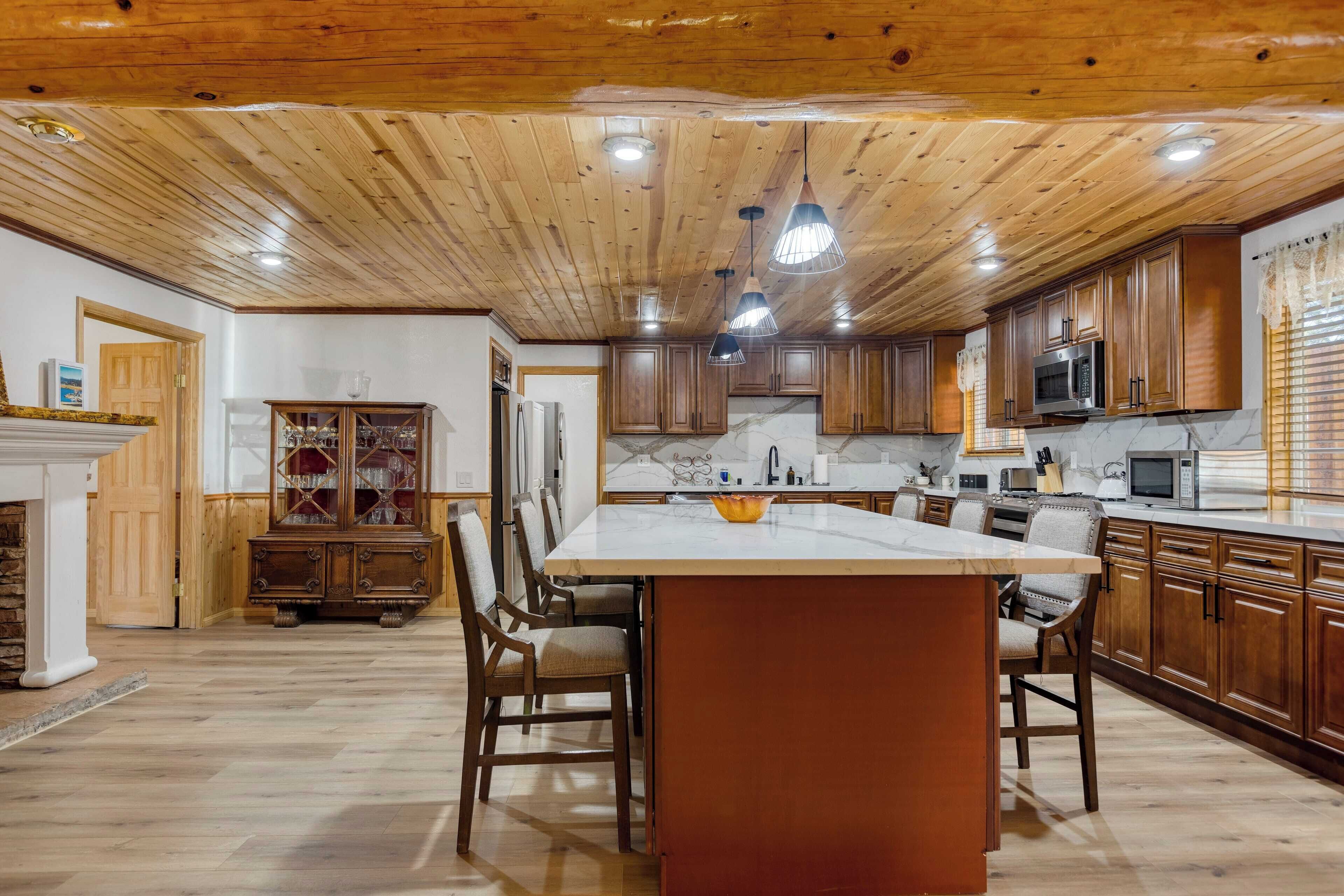 Una cocina amplia con armarios de madera, una isla de mármol e iluminación colgante.