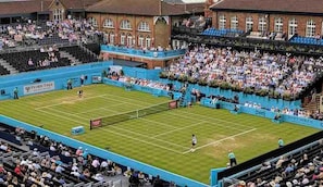 Una cancha de tenis rodeada por una gran multitud en un estadio al aire libre.