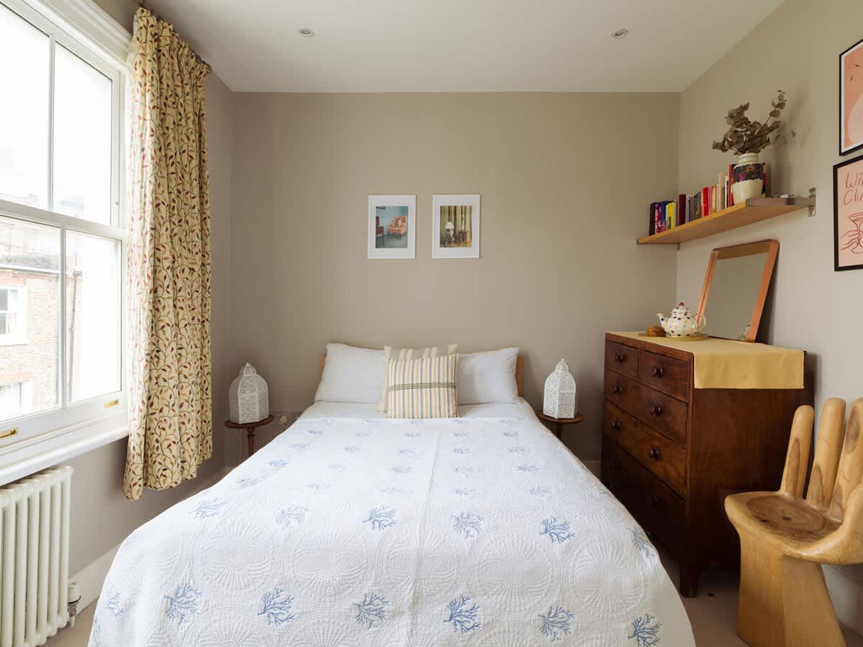 A bedroom with a bed, a dresser, a chair, and a window with curtains.