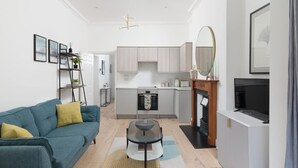 Una sala de estar moderna con sofá, mesa de centro y una cocina al fondo.