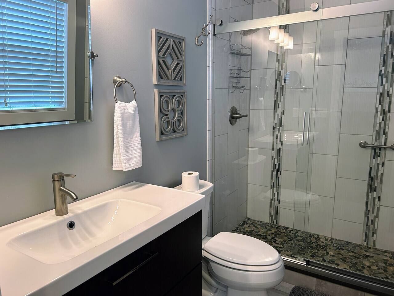 Full bathroom attached to the master bedroom with a king bed, featuring a modern design and a walk-in tiled shower with a glass door - a stylish and comfortable space for relaxation.