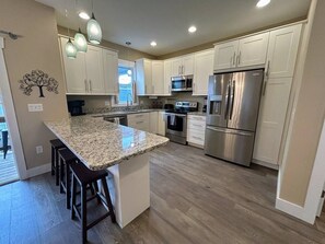 A modern kitchen with granite countertops, stainless steel appliances, and a central island with bar stools.