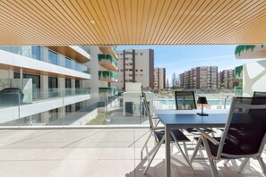 Un área de estar moderna al aire libre con vista a la piscina, barandillas de vidrio y techo de madera.