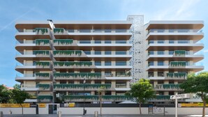 En byggnad med flera våningar, balkonger, en centralt placerad dekorativ struktur och skyltar med texten ”DUNNES STORES”.
