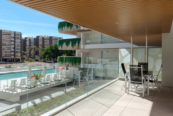 A modern outdoor lounge area with a pool, glass walls, and a dining setup.