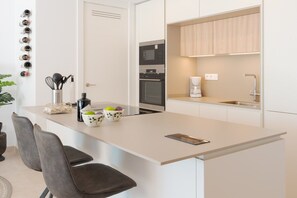 Una cocina moderna con una isla central, microondas, horno y cafetera.
