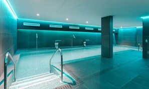 Une piscine intérieure moderne, dotée de plusieurs couloirs de nage, d’une eau claire et d’un sol carrelé.