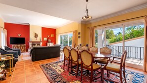 A living room with a sofa, TV, and dining area with chairs and a table. - Villa Amland | Golf Paradise with private swimming pool (Mijas)
