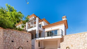 A two-story house with a stone facade, a balcony, and a garage. - Villa Amland | Golf Paradise with private swimming pool (Mijas)